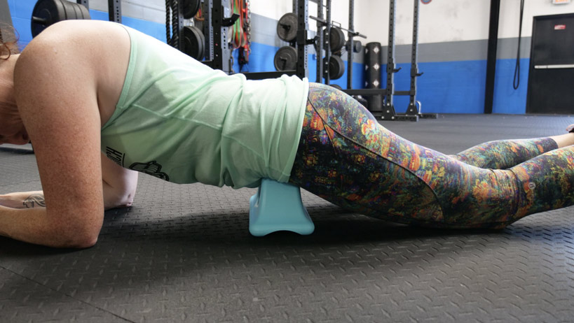 A woman demonstrating the Psoas Quick Release Self-Massage Tool